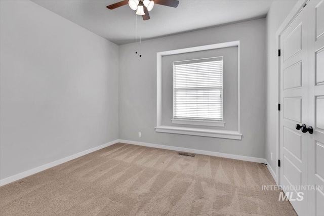 spare room featuring a ceiling fan, carpet, and baseboards