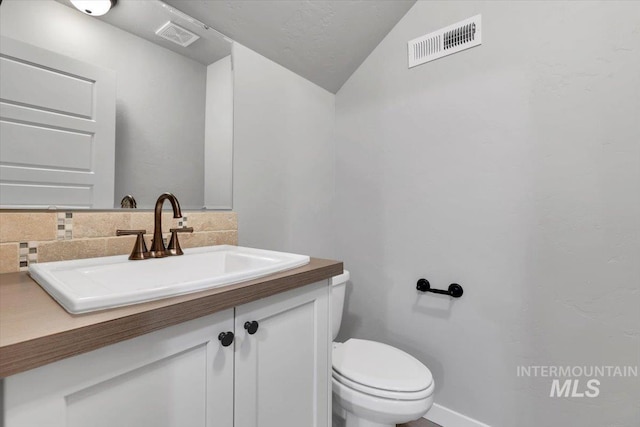 bathroom featuring vanity, visible vents, toilet, and vaulted ceiling