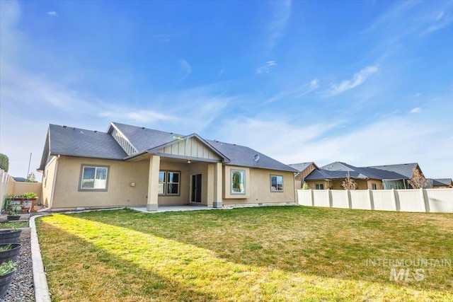 rear view of property featuring a patio, a yard, stucco siding, and fence