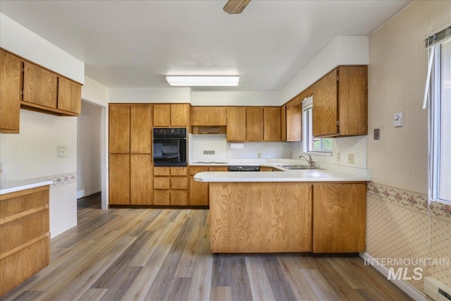 2011 Schodde, Burley, ID 83318 - kitchen featuring black oven, a sink, brown cabinetry, and wallpapered walls