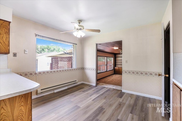 2011 Schodde, Burley, ID 83318 - unfurnished dining area featuring plenty of natural light, wood finished floors, a baseboard radiator, wainscoting, and ceiling fan