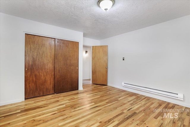 2011 Schodde, Burley, ID 83318 - unfurnished bedroom featuring a baseboard heating unit, wood finished floors, a closet, a textured ceiling, and baseboards
