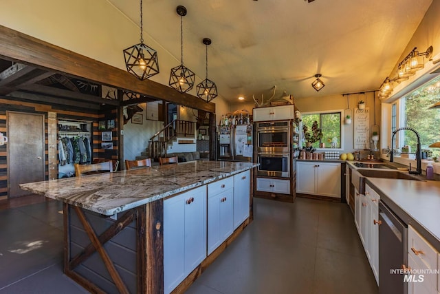 kitchen featuring a breakfast bar, white cabinetry, stainless steel appliances, decorative light fixtures, and dark stone countertops