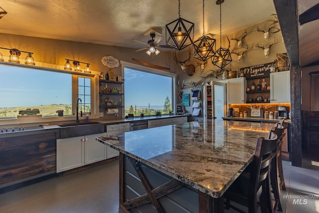 kitchen featuring pendant lighting, white cabinets, a breakfast bar, and sink