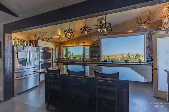 kitchen featuring lofted ceiling with beams, white cabinetry, stainless steel appliances, a kitchen bar, and decorative light fixtures