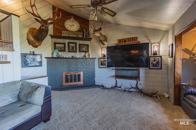 carpeted living room with a brick fireplace, lofted ceiling, wood walls, and ceiling fan