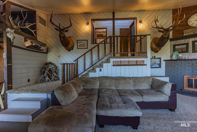 carpeted living room with a brick fireplace and wood walls