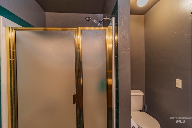 bathroom with a shower with door and toilet