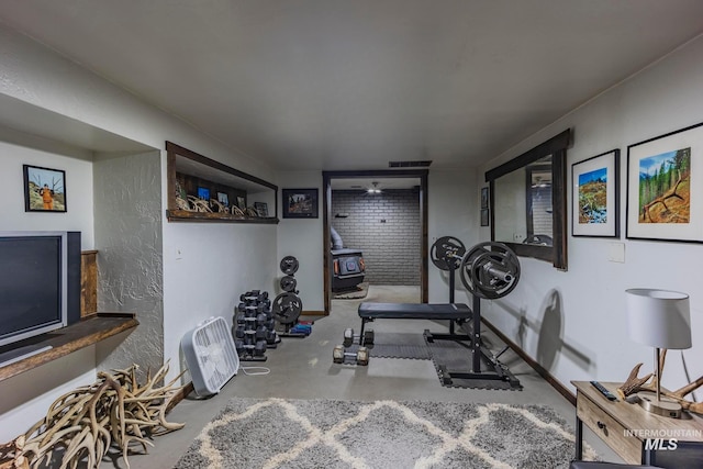 exercise room featuring a wood stove and concrete flooring