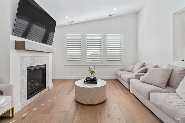 living room with a fireplace, vaulted ceiling, and light hardwood / wood-style flooring