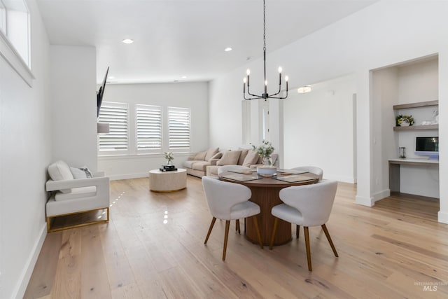 dining space with lofted ceiling, a chandelier, and light wood-type flooring