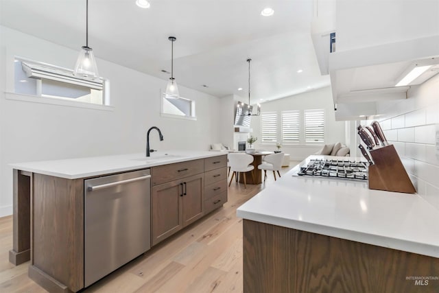 kitchen featuring sink, decorative light fixtures, light hardwood / wood-style flooring, appliances with stainless steel finishes, and plenty of natural light