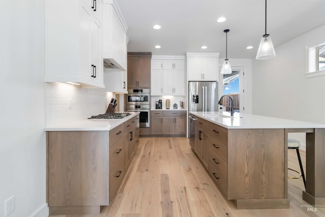 kitchen featuring a spacious island, white cabinetry, pendant lighting, stainless steel appliances, and backsplash