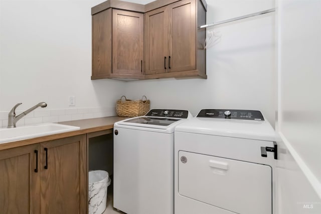 clothes washing area featuring cabinets, sink, and washer and dryer