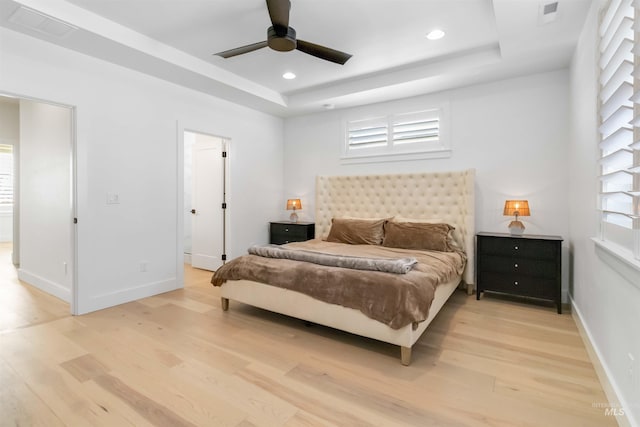 bedroom with a tray ceiling, light hardwood / wood-style flooring, and ceiling fan