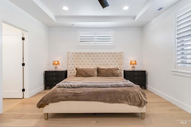 bedroom featuring a raised ceiling and light hardwood / wood-style floors