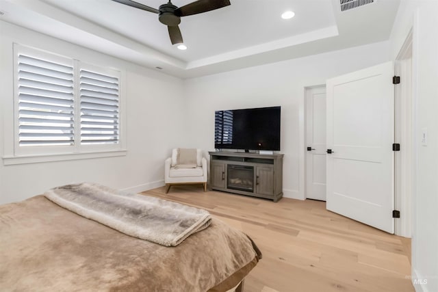 bedroom featuring a raised ceiling, ceiling fan, and light hardwood / wood-style floors