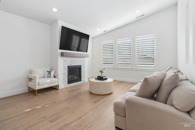 living room with lofted ceiling, light hardwood / wood-style flooring, and a tile fireplace