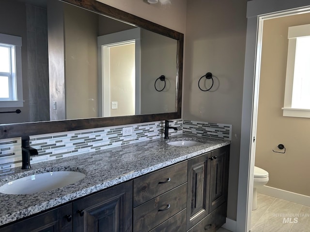 bathroom featuring toilet, vanity, and backsplash