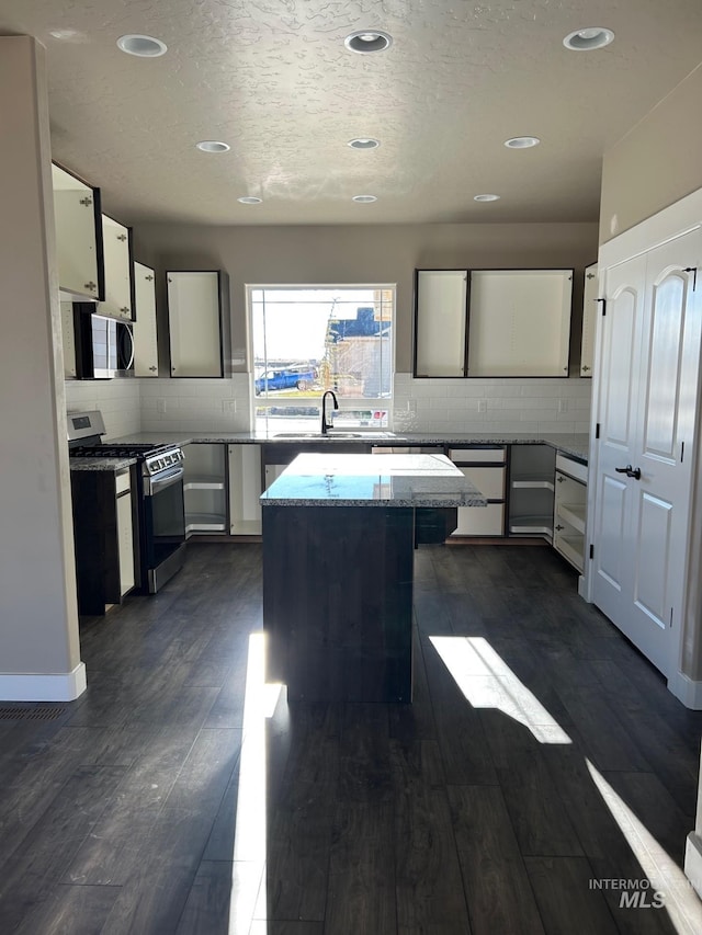 kitchen featuring a center island, sink, light stone countertops, appliances with stainless steel finishes, and dark hardwood / wood-style flooring