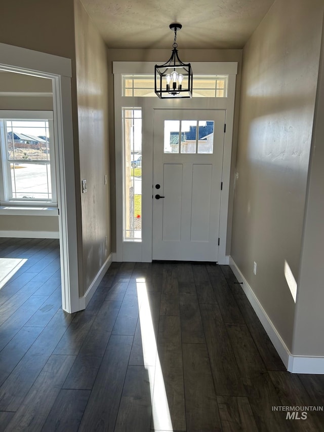 entryway featuring dark wood-type flooring and a notable chandelier