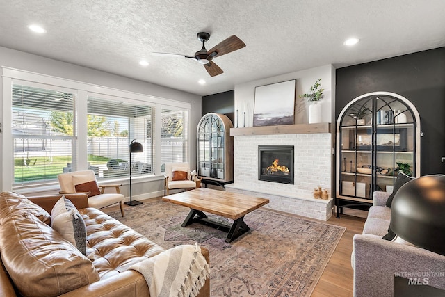 living room featuring a fireplace, light hardwood / wood-style flooring, and a textured ceiling