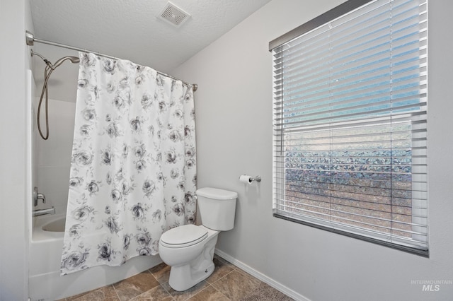 bathroom featuring shower / tub combo with curtain, toilet, and a textured ceiling