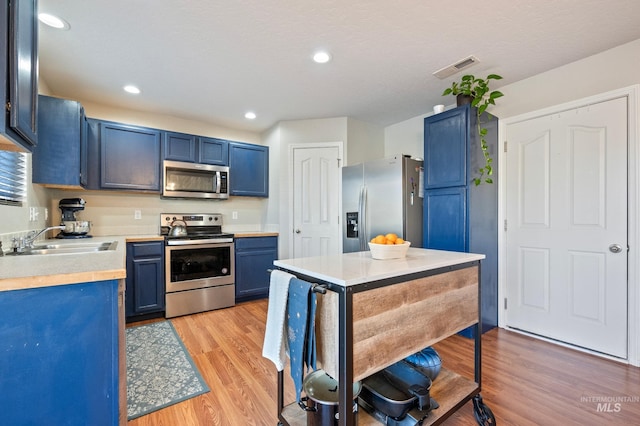 kitchen featuring blue cabinetry, appliances with stainless steel finishes, light hardwood / wood-style floors, and sink