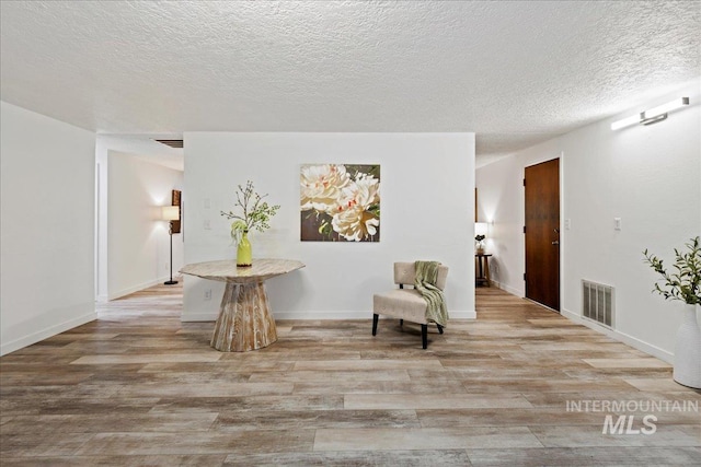 unfurnished room featuring light hardwood / wood-style floors and a textured ceiling