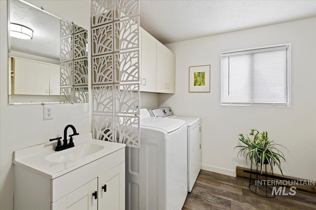 clothes washing area featuring cabinets, a textured ceiling, dark wood-type flooring, sink, and separate washer and dryer