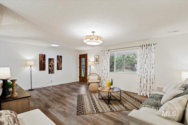 living room with a textured ceiling and dark hardwood / wood-style floors