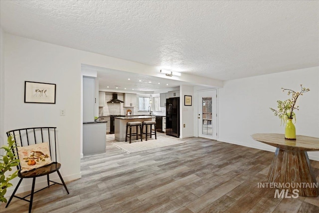 living room with a textured ceiling, light wood-type flooring, and sink