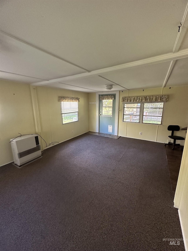 empty room featuring dark colored carpet and heating unit