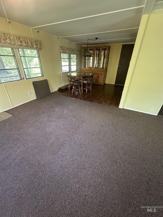 unfurnished dining area featuring dark carpet and dark wood finished floors