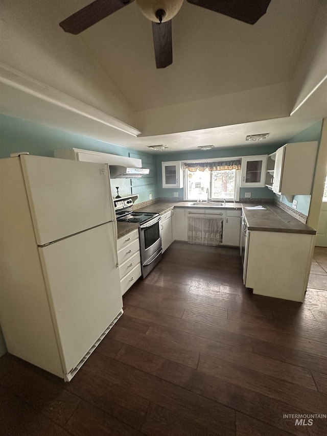 kitchen featuring dark countertops, stainless steel range with electric cooktop, lofted ceiling, dark wood-type flooring, and freestanding refrigerator