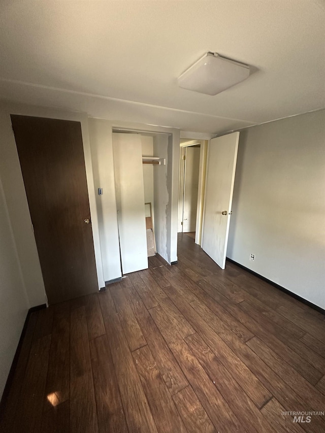 unfurnished bedroom featuring baseboards and dark wood-style floors