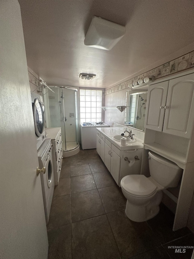 full bathroom featuring a shower stall, tile patterned floors, toilet, vanity, and washer / clothes dryer