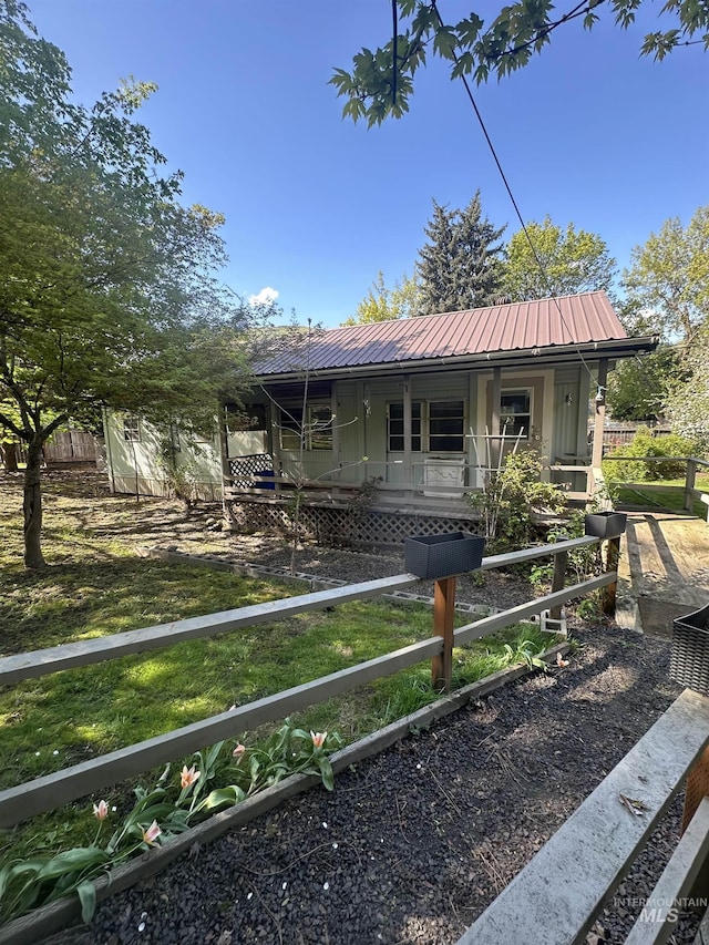 bungalow-style house with metal roof, fence private yard, a front yard, and covered porch