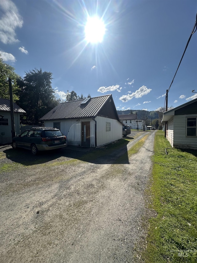 view of side of property with driveway and metal roof
