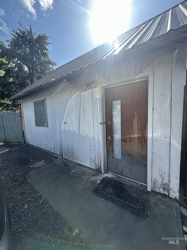 entrance to property featuring fence and metal roof