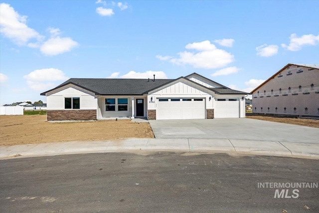 view of front of home with a garage, stone siding, driveway, and board and batten siding