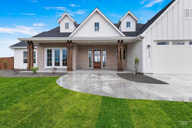 modern inspired farmhouse with a front lawn, covered porch, and a garage