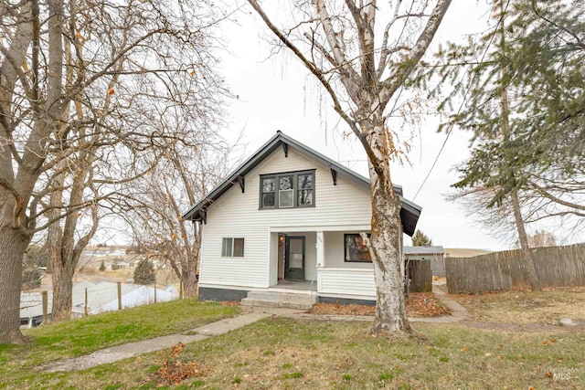 view of front of house featuring a front yard, covered porch, and fence