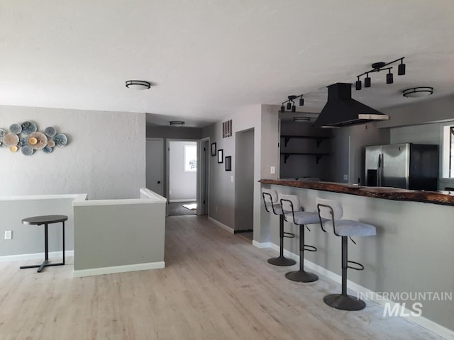 39992 Waha Glen Rd, Lewiston, ID 83501 - kitchen featuring island exhaust hood, wood finished floors, a kitchen breakfast bar, stainless steel fridge, and baseboards