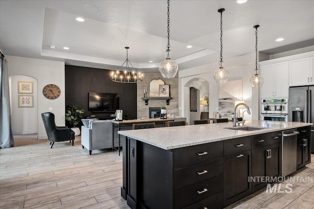 2357 N Synergy Pl, Eagle, ID 83616 - kitchen with a sink, arched walkways, white cabinetry, an island with sink, and dark cabinets