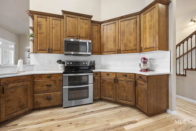 kitchen featuring appliances with stainless steel finishes, light hardwood / wood-style floors, sink, and tasteful backsplash