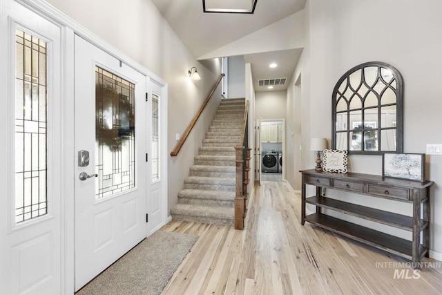 entryway featuring high vaulted ceiling, light wood-type flooring, washer / clothes dryer, and a wealth of natural light