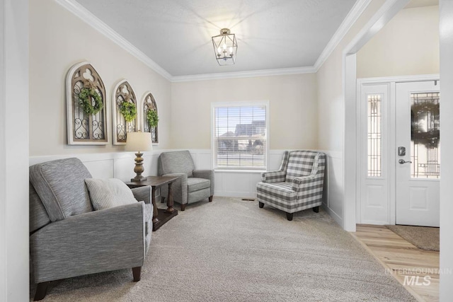 living area with crown molding, an inviting chandelier, and light hardwood / wood-style flooring