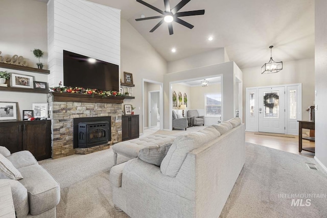 living room with ceiling fan with notable chandelier, light wood-type flooring, and high vaulted ceiling