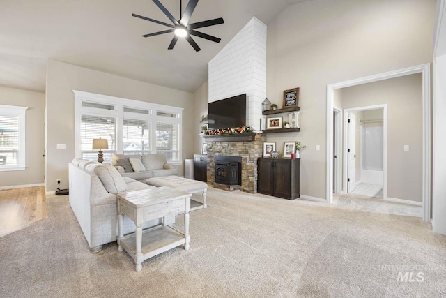 carpeted living room with high vaulted ceiling, a wood stove, and ceiling fan